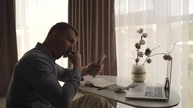 A grown man wipes snot on  100 dollars bills. Family budget. 