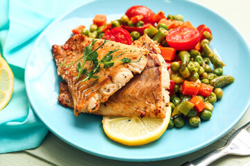 Plate with tasty baked cod fillet and vegetables on color wooden background, closeup
