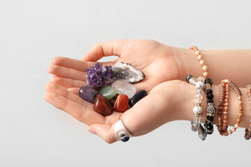 Female hands with beautiful gemstones on light background