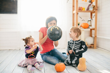 Happy family of mother and children prepare for Halloween in decorate the home
