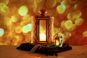 Islamic lamps with tasbih and carpet against blurred lights
