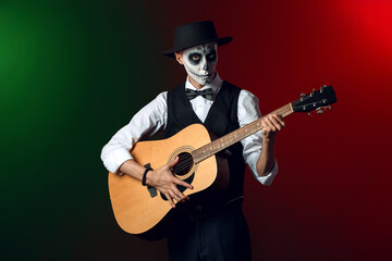 Young man with painted skull on his face and guitar against dark background. Celebration of Mexico's Day of the Dead (El Dia de Muertos)