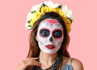 Young woman with painted skull on her face against color background. Celebration of Mexico's Day of...