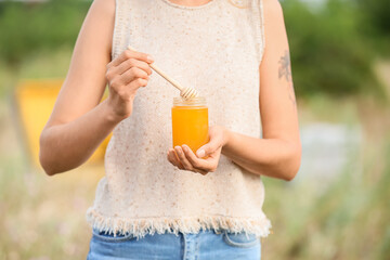 Female beekeeper with sweet honey at apiary