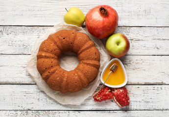 Bread with honey, pomegranate and apples on white wooden background. Rosh hashanah (Jewish New Year) celebration