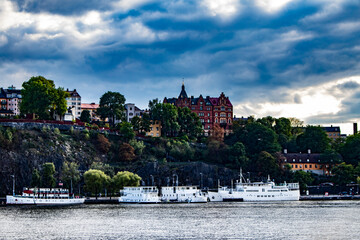 Naklejka premium Boats and Traditional Buildings Line the Rocky Cliffs of the Katarina-Sofia Island Coastline in Stockholm, Sweden