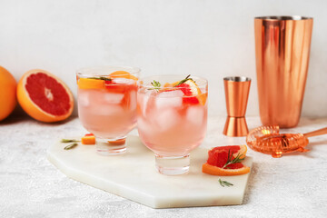 Glasses of tasty grapefruit margarita on light background