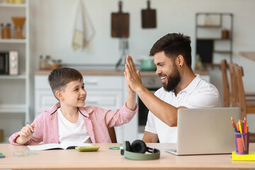 Little boy with his father giving each other high-five at home