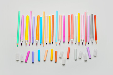 Colorful markers and pencils on light background