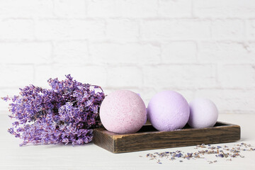 Tray with bath bombs and lavender flowers on light background