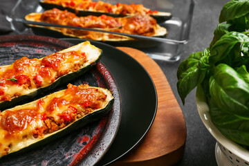 Plate with meat stuffed zucchini boats on dark background, closeup