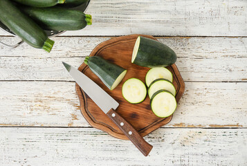 Board with sliced zucchini squash on light wooden background