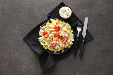 Plate of tasty Caesar salad and sauce on black background
