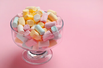 Glass bowl with sweet marshmallows on pink background