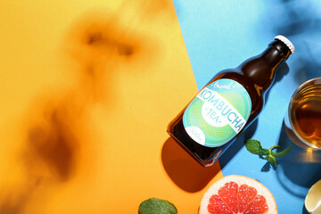 Glass and bottle of natural kombucha tea on color background