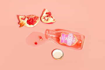 Composition with spilled kombucha tea and pomegranate on color background