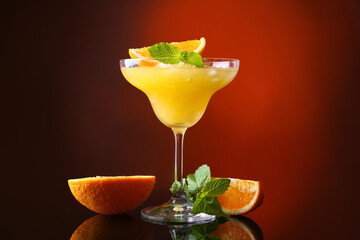 Glass of tasty orange margarita cocktail on dark color background