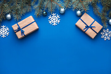 Christmas fir branches with presents and snowflakes on blue background