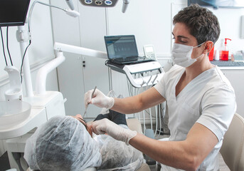 Odontólogo con barbijo en su consultorio atiende la consulta de un paciente - obrazy, fototapety, plakaty