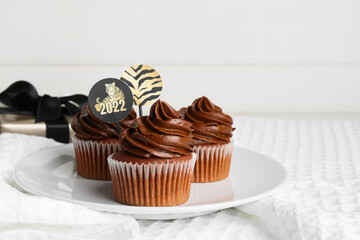 Plate with tasty cupcakes for New Year 2022 celebration on table
