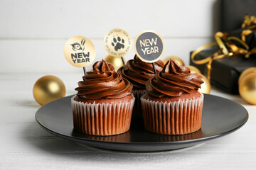 Plate with tasty cupcakes for New Year 2022 celebration on table