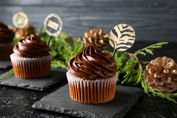 Tasty cupcake for New Year 2022 celebration on dark background