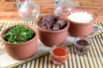 delicious Brazilian food feijoada with beans, pork, bacon, sausage with cabbage, rice, salad, spices and pepper. rustic cuisine.