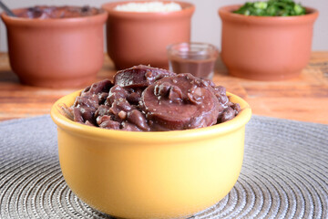 delicious Brazilian food feijoada with beans, pork, bacon, sausage with cabbage, rice, salad, spices and pepper. rustic cuisine.