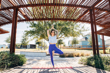 Woman practicing yoga tree pose outdoors in park