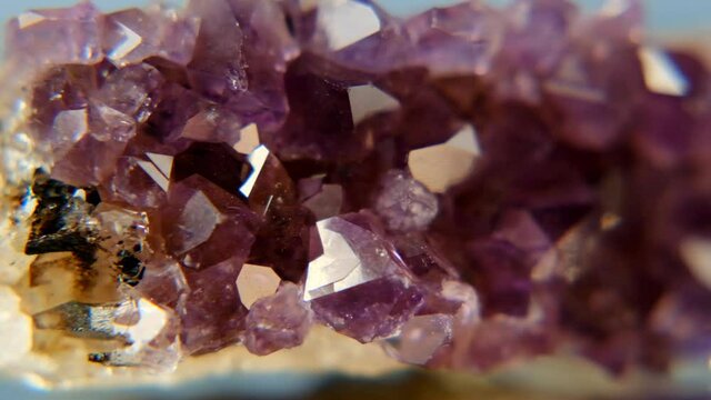 Amethyst purple crystal close-up- Amethyst stone on a blue background. Texture of amethyst druse close-up. High quality 4k footage