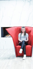 rockstar vampire girl waits on red armchair