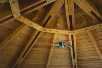 A flying unmanned aerial vehicle under a wooden roof.