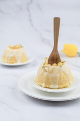 Homemade lemon cake classic recipe, decorated with sugar icing on marble table. Healthy organic summer dessert pie with yellow tulip on background. 