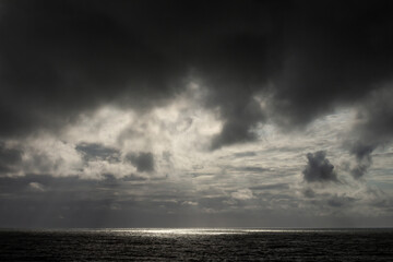 Storm clouds over the sea. Reflections of the sun in the sea water.