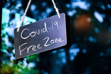 A notice label ‘Covid-19 Free Zone’ which hanging on the glass door of the shop, concept for informing customers in Covid-19 crisis situations around the world.