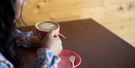 Selective focus shot of a coffee latte cup from above. An unrecognizable young woman holding coffee cup decorated professionally. 