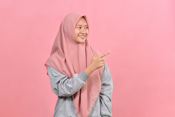 Fototapeta premium Young Asian muslim woman points a copy space