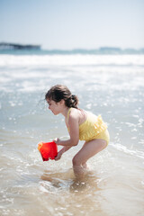 child playing on the beach with bucket in ocean