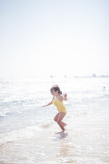 Fototapeta na wymiar child playing on the beach in ocean on sunny day