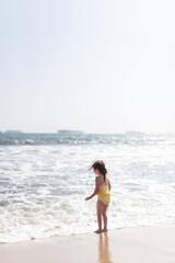 child on the beach looking at ocean on sunny day