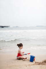 Young child playing in the sand building sandcastle at the beach