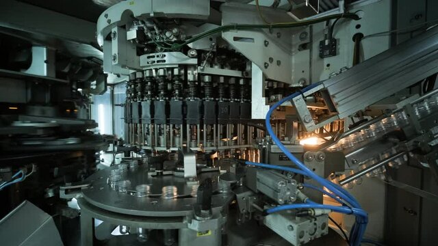Automatic filling machine pours water into plastic PET bottles at modern beverage plant