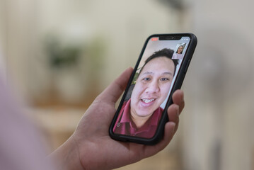 Focusing at hand with phone while a woman using video calling with husband
