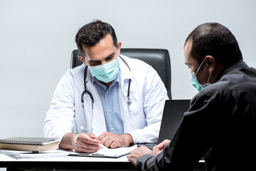 The Asian Muslim man doctor was sitting at the patient's examination table and was examining and talking about the patient with a smiling and worried face.