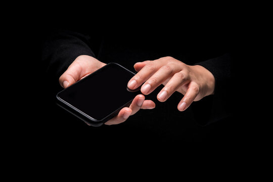 The image close-up of the hand of a woman using a mobile phone, on black background.