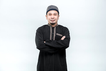 Obraz na płótnie Canvas The image of an Asian Muslim man standing with his arms crossed with a smiling face, on white background.