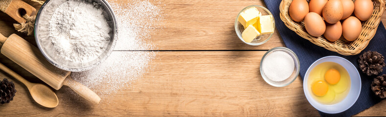 Baking utensils and cooking ingredients for cake bakery include flour, butter, sugar, eggs, and tools on the table, top view with copy space.