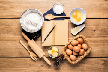 Fototapeta na wymiar Pictures of ingredients for making cakes bakery around, such as eggs, flour, sugar, butter, recipe book, and equipment for making on a wooden floor, with copy space.