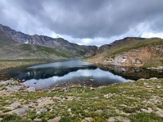 Summit Lake on Mount Evans, Colorado under dramatic summer cloudscape reflected in still water of lake..