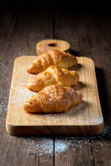 The newly baked croissant is placed on a wooden tray placed on a wooden table.